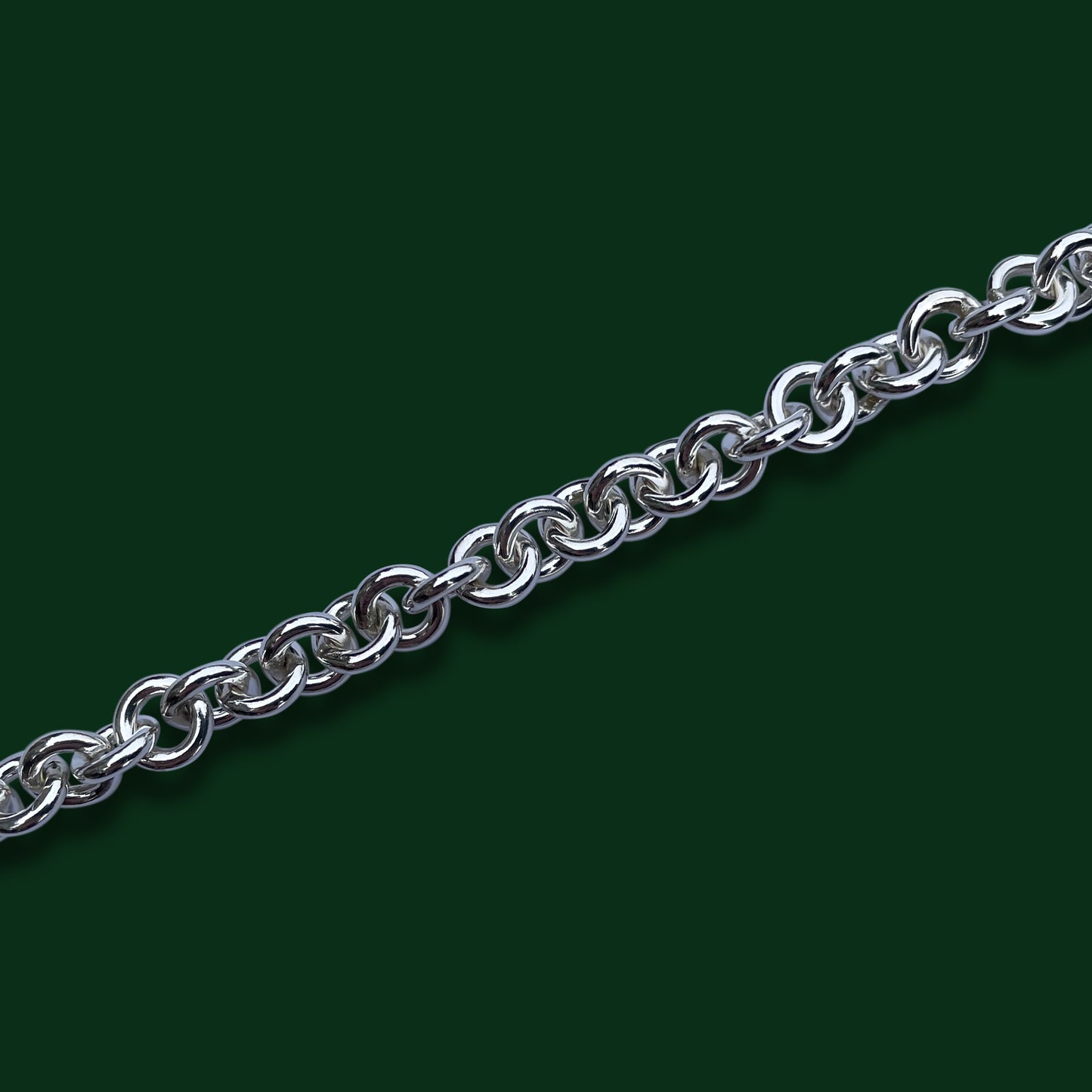 A close up of Timio's Carnival chain on a dark green background.