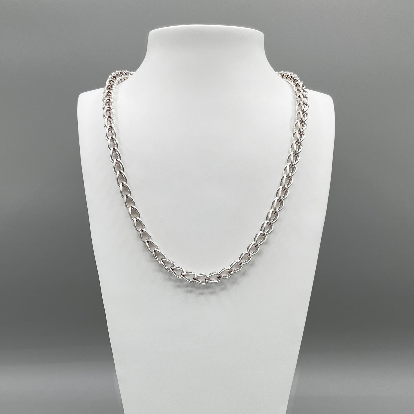 A photo of the Kubos chain in fine silver, displayed on a white bust in front of a grey background.