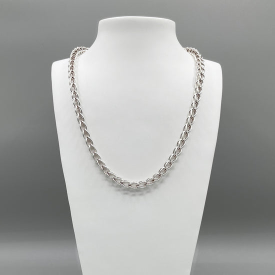 A photo of the Kubos chain in fine silver, displayed on a white bust in front of a grey background.