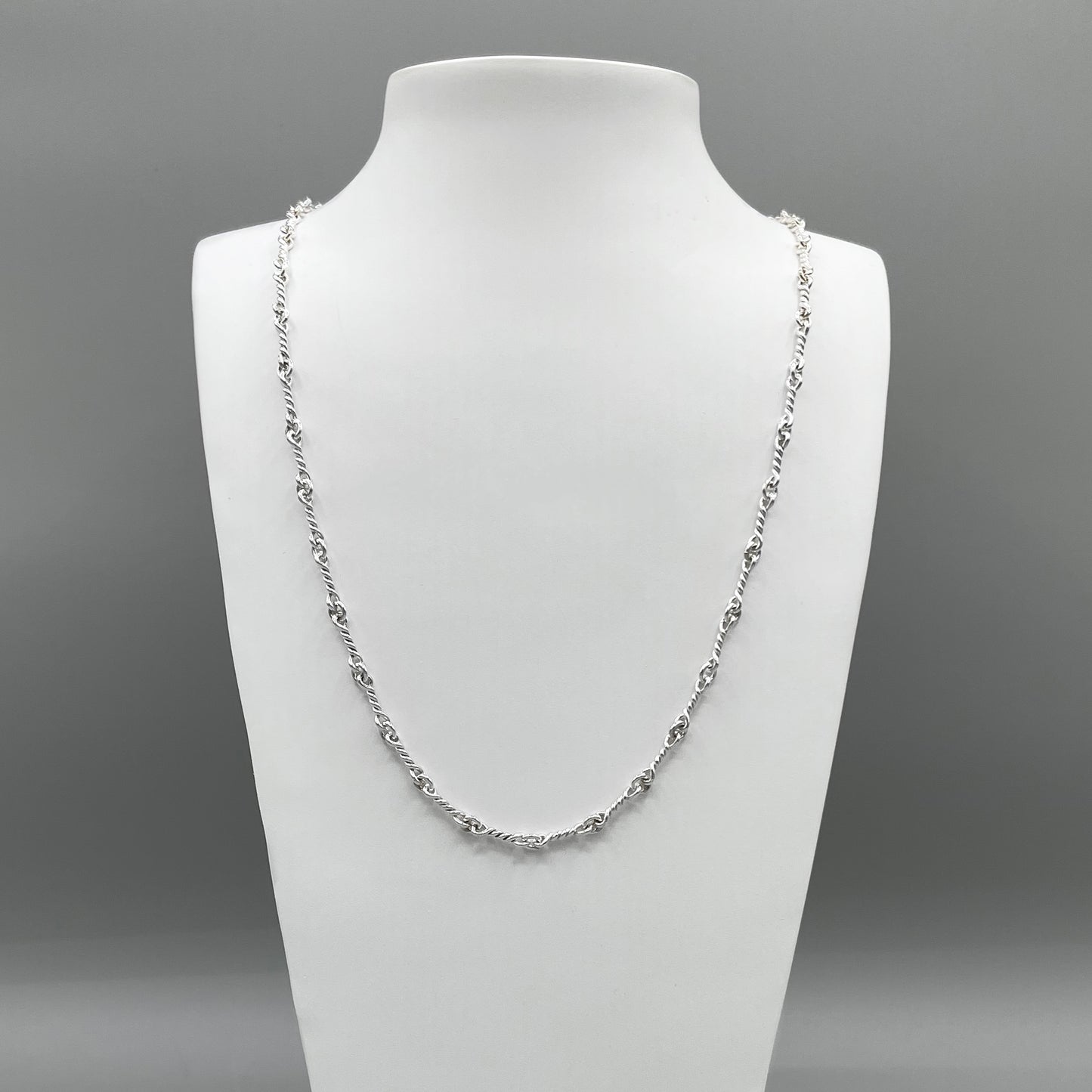 A photo of the Nautical chain in fine silver, on a white bust in front of a grey background.